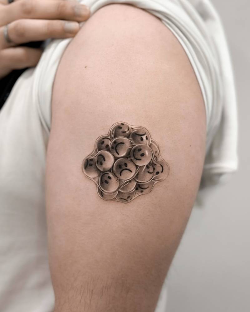 Smiley and sad faces tattooed on the upper arm.