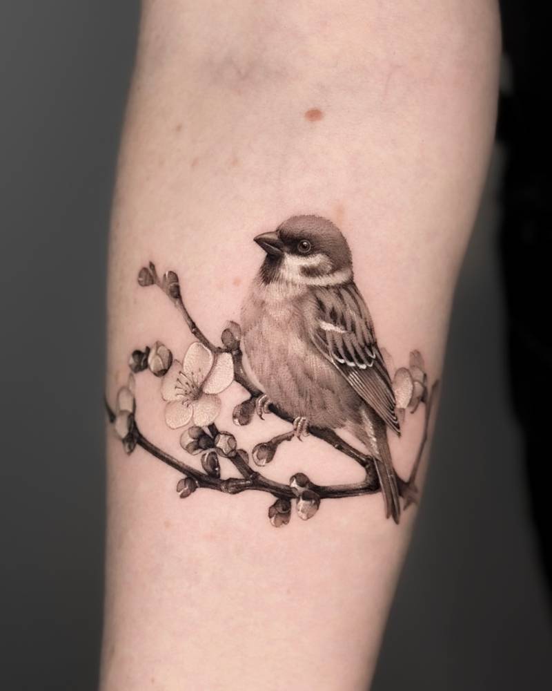 Cherry blossom branch and sparrow tattoo located on the inner forearm.
