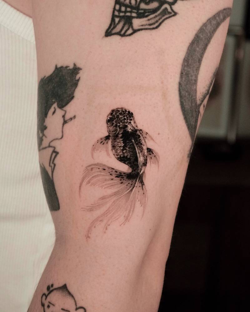 Goldfish tattoo in micro-realistic style located on the upper arm.
