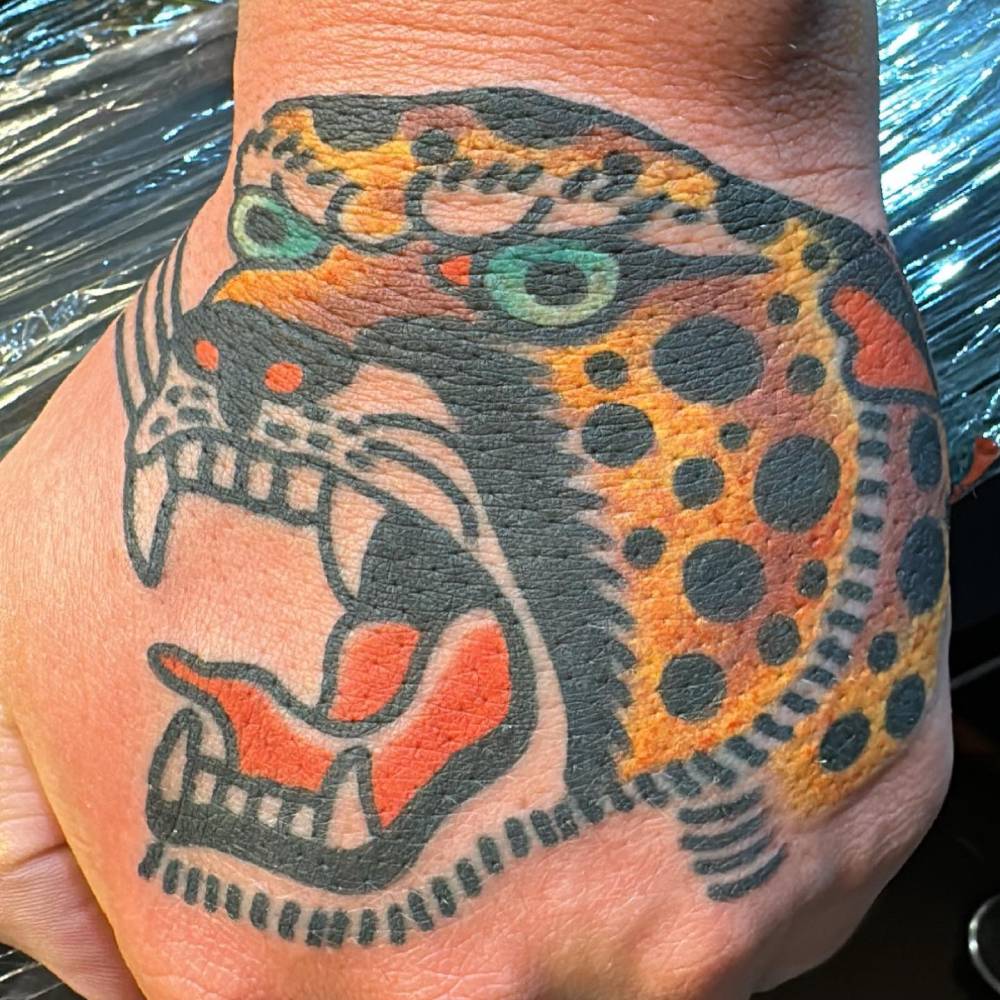 Traditional style leopard head tattoo located on the hand.