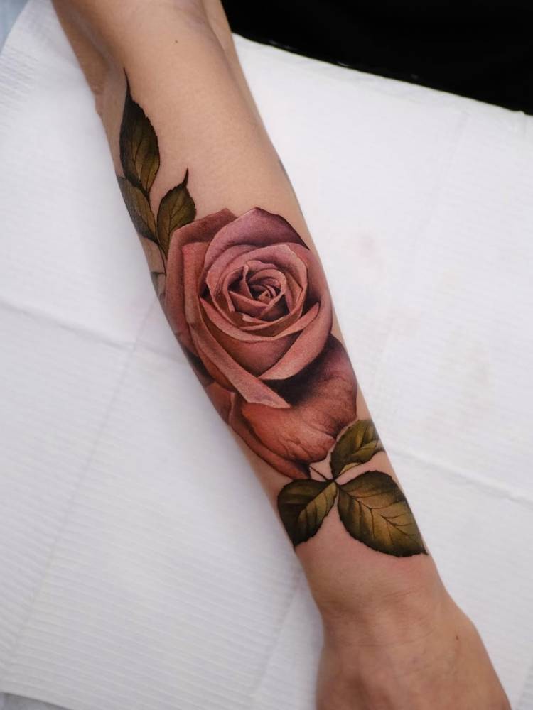 Pink rose tattio located on the forearm, realistic style.