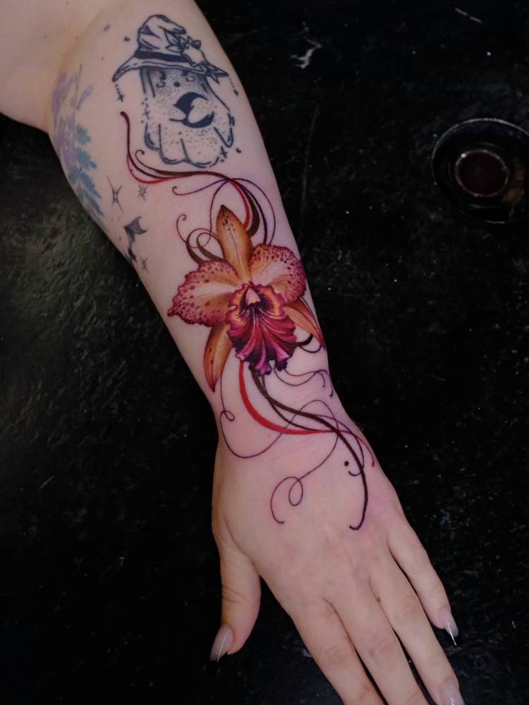 Realistic style orchid tattoo placed on the forearm.