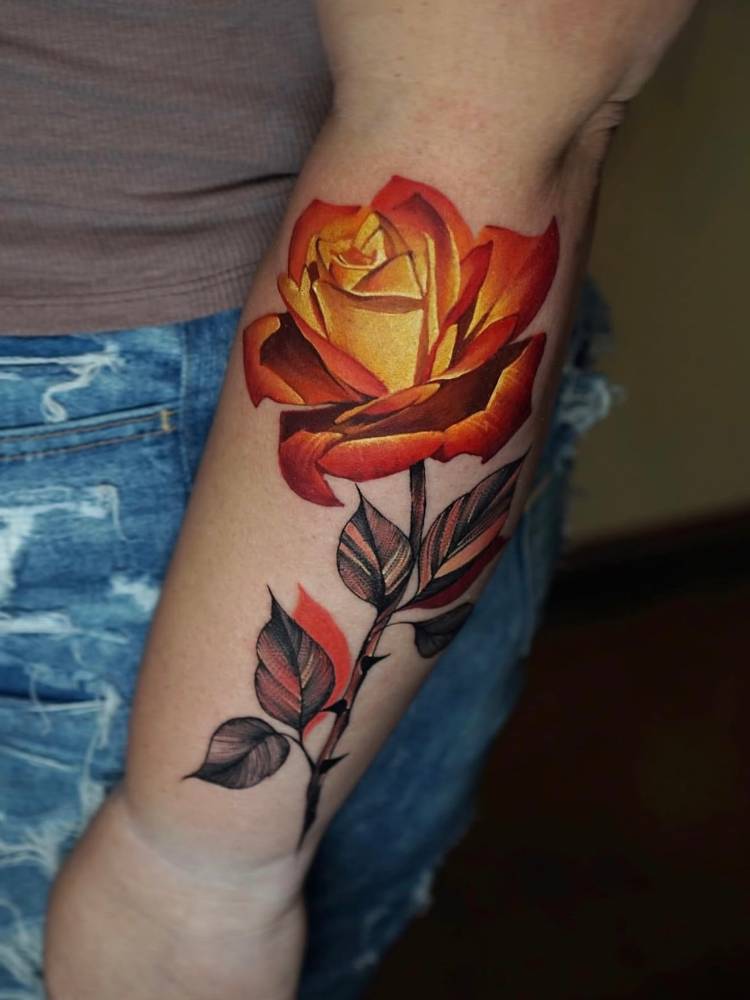 Orange rose tattoo in realistic style located on the forearm.