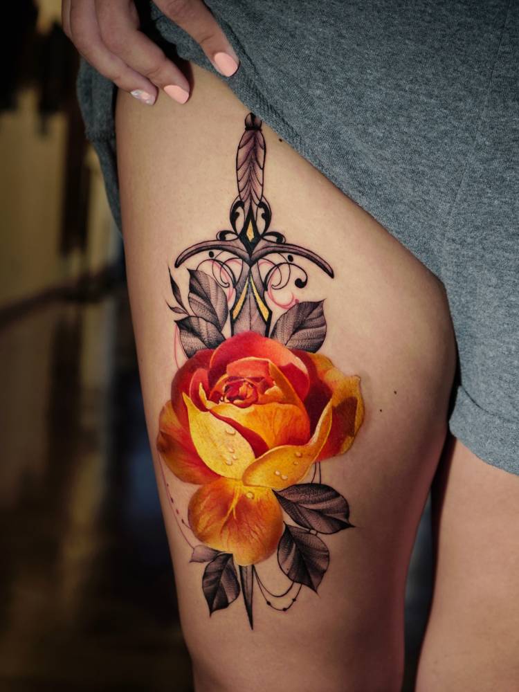 Orange rose and dagger tattoo placed on the thigh.
