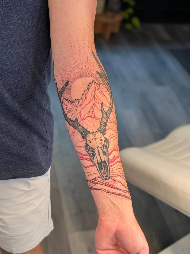 Deer skull tattoo located on the inner forearm, illustrative style.