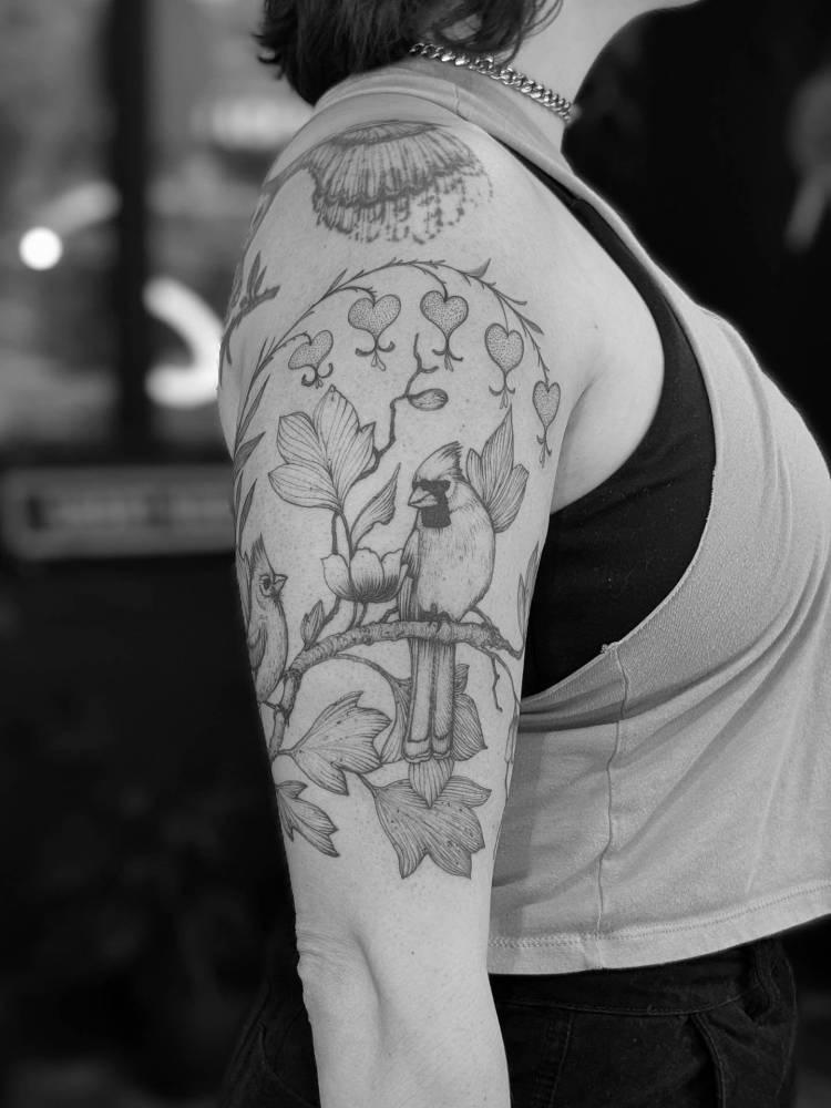 Cardinal on a branch tattoo located on the upper arm, illustrative style.