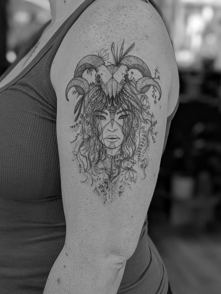 Female warrior portrait in illustrative style tattooed on the upper arm.