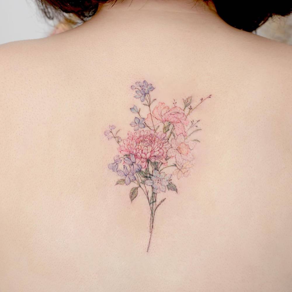 Watercolor style flower bouquet tattoo done on the upper back.