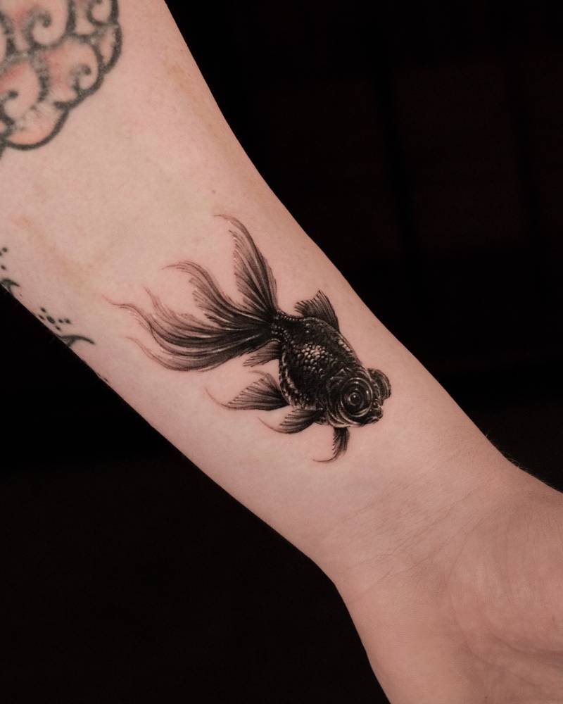 Goldfish tattoo located on the wrist, micro-realistic style.