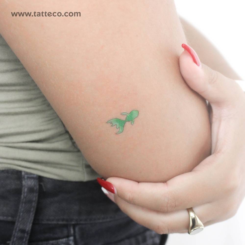 Tiny green fish temporary tattoo located on the tricep.