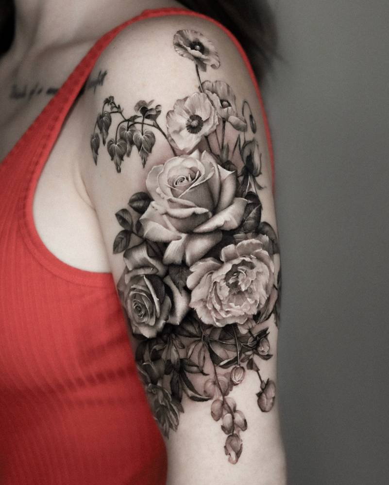 Black and grey flower bouquet tattoo located on the upper arm.