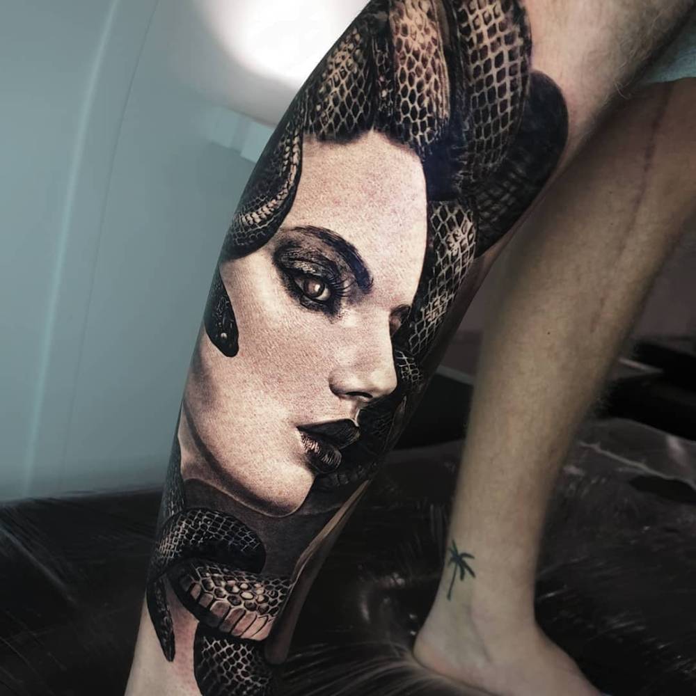Black and grey Medusa portrait tattoo located on the shin.