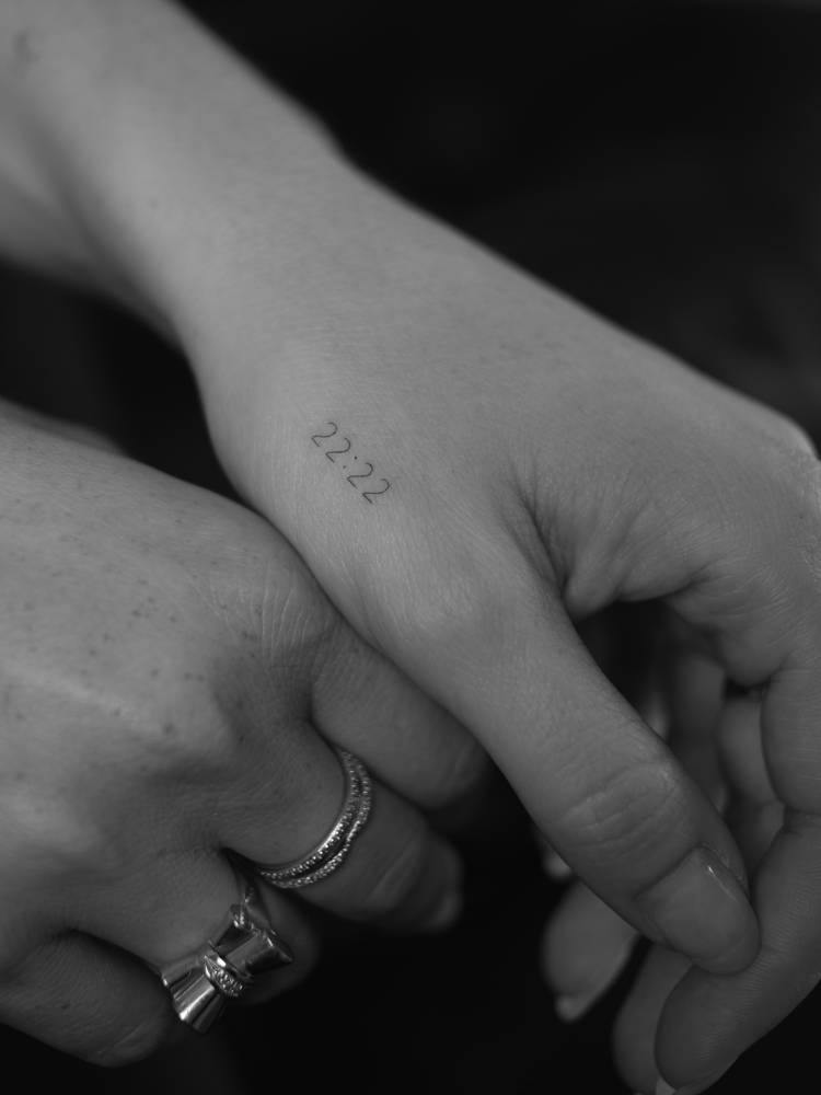 Angel number "22:22" tattoo located on the hand.