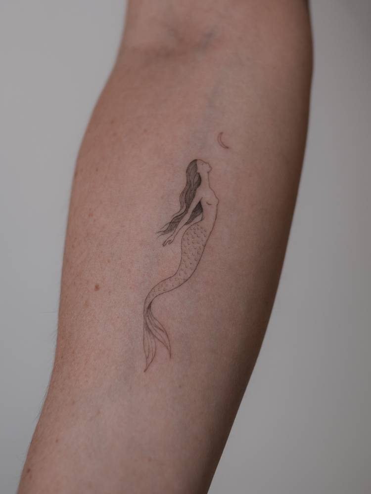 SIngle needle mermaid tattoo located on the inner forearm.