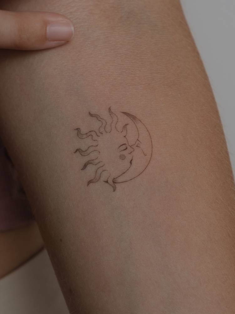 Kissing sun and moon tattoo placed on the inner forearm.