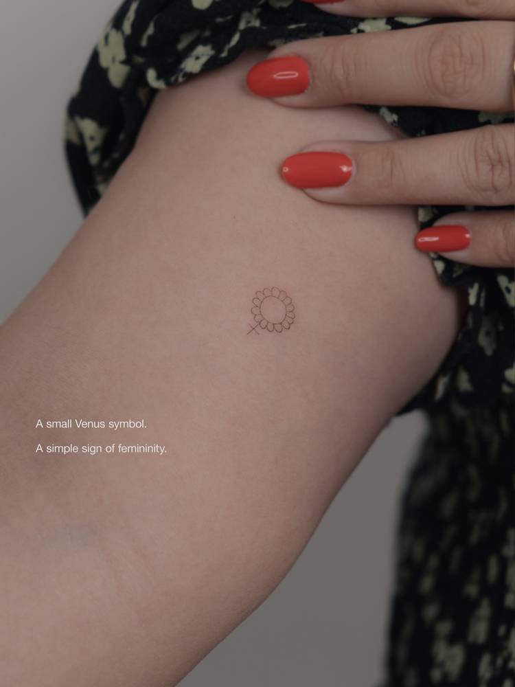 Floral venus symbol tattoo located on the inner arm, minimalist style.