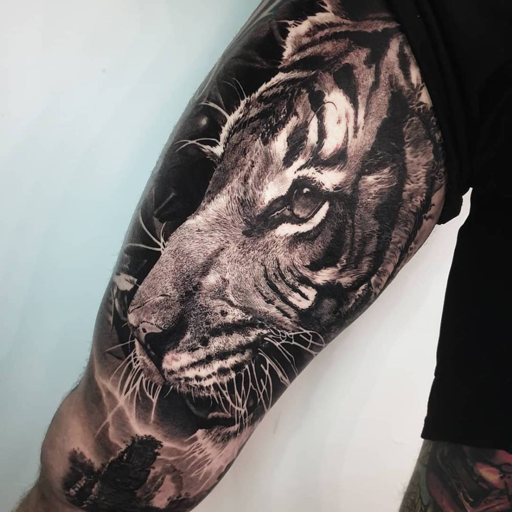 Black and grey tiger head tattoo located on the thigh.