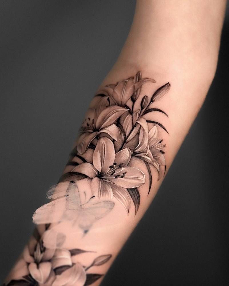 Lily flowers tattooed on the inner forearm, black and grey style.