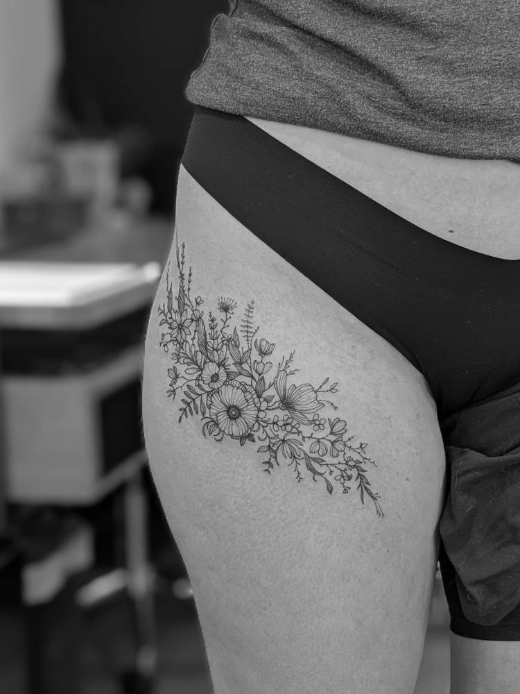 Freehand floral design tattooed on the thigh.