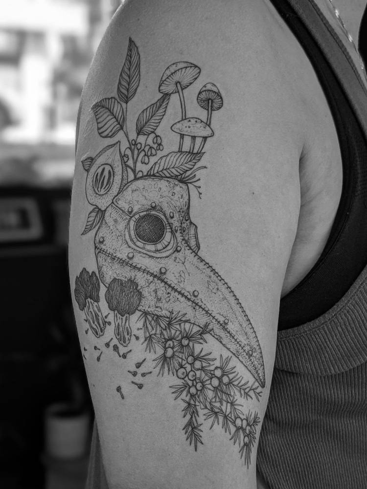Plague mask tattooed on the upper arm.
