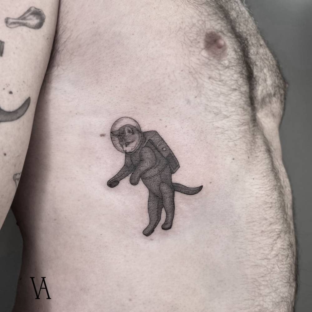 Cat astronaut tattoo located on the rib, illustrative style.
