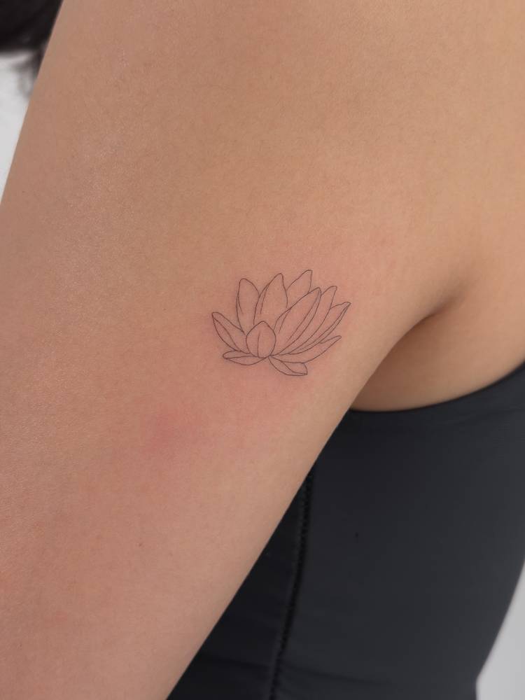 Fine line style lotus flower tattoo located on the tricep.
