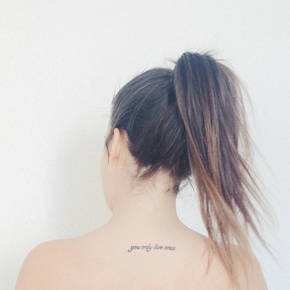 Upper back tattoo saying "You only live once" on Úrsula Campos.