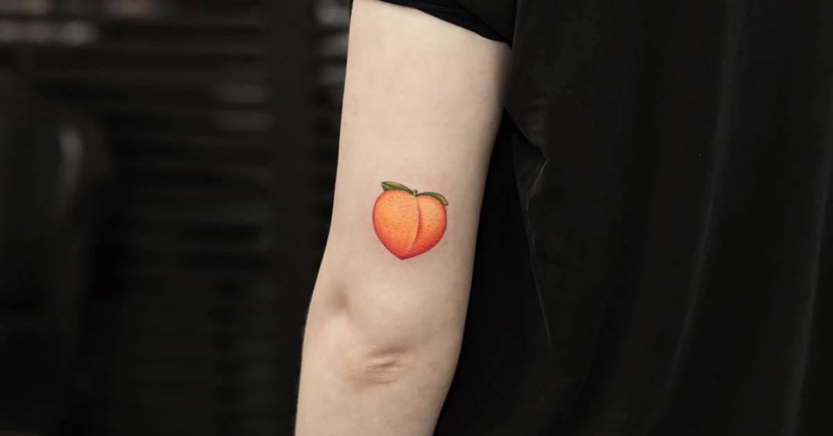 Peach emoji tattoo on the back of the left arm.